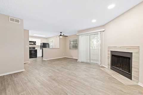 a living room with a fireplace and a kitchen in the background